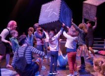 Production image from The Chit Chat Chalk Show. Children and actors are holding large black foam cubes which have been drawn on with blue chalk