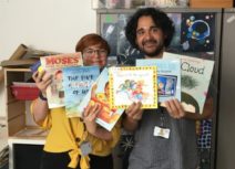 Photo of Z-arts development manager Gemma, and Finance and Administration Officer Ramsey holding children's books donated from Amazon Wishlist
