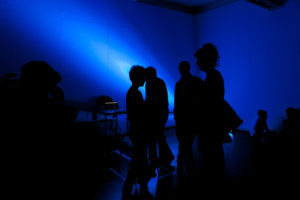 Group of people of silhouetted by dark blue light