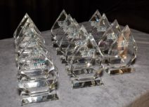 Photo of 15 North West Charity Award trophies lined up on a table with a grey velvet tablecloth