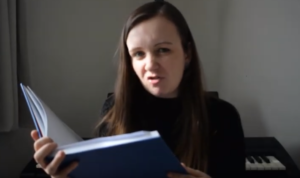 Photo of a young woman reading from a large blue book. The story is Peter Pan.