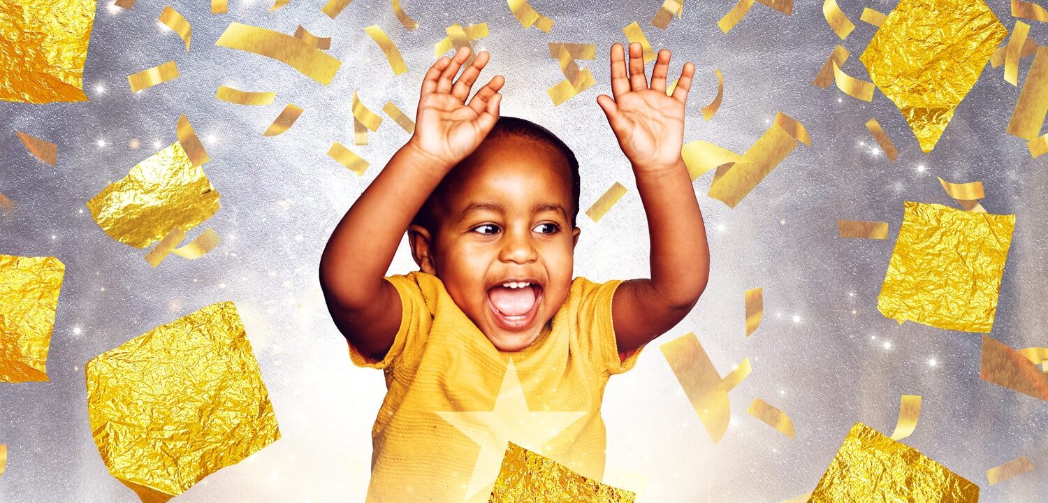 A happy young child cheering amidst falling gold foil confetti and stars.